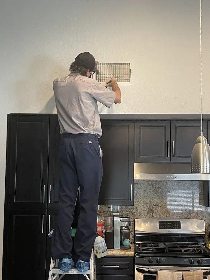 Technician inspecting an air vent during HVAC service in De Soto